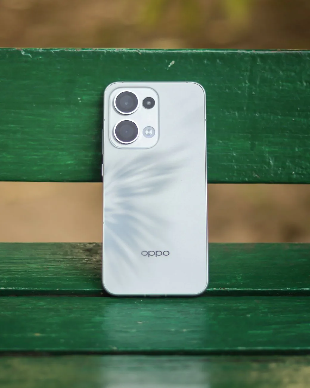 smartfon Oppo na zielonej drewnianej ławce na zewnątrz — Dlaczego nie bierzemy OPPO Reno 11 do naprawy