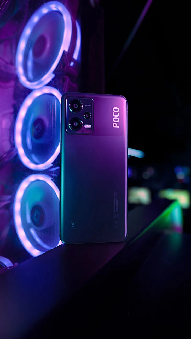 smartfon Poco ustawiony pionowo na tle neonowego stanowiska gamingowego — Dlaczego nie bierzemy POCO F4 do naprawy