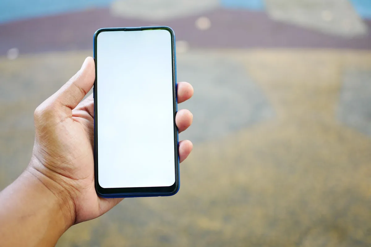 dłoń trzymająca smartfon z białym ekranem — Dlaczego nie bierzemy Redmi A1 do naprawy