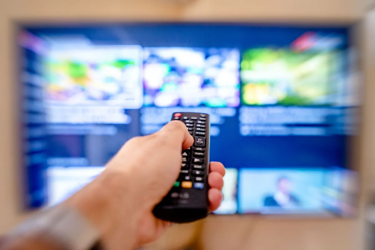 dłoń z pilotem wycelowanym w telewizor w pokoju — Dlaczego nie bierzemy Sony BRAVIA X80L do naprawy