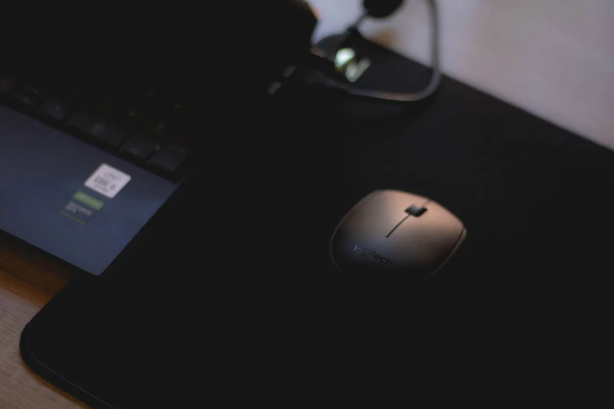 mysz bezprzewodowa na czarnej podkładce obok laptopa — Dlaczego nie bierzemy SteelSeries Rival 5 do naprawy