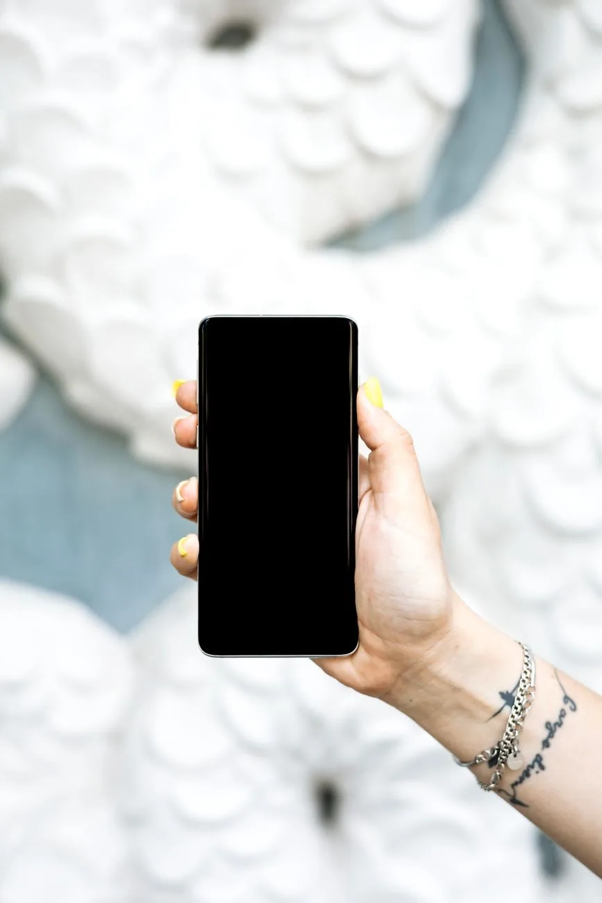 dłoń trzymająca czarny smartfon z dotykowym ekranem — Dlaczego nie bierzemy Xiaomi Mi 8 do naprawy