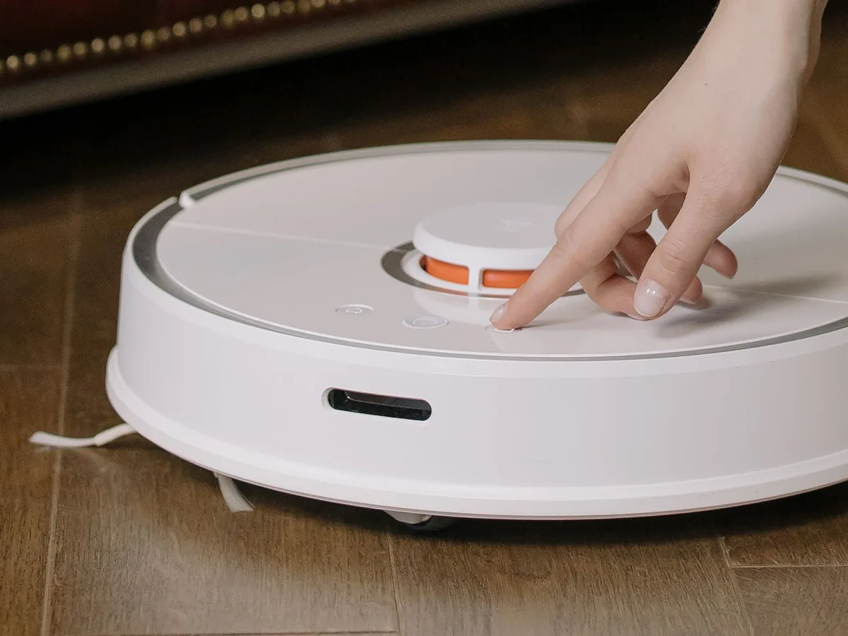 dłoń wciskająca przycisk na robocie sprzątającym — Dlaczego nie bierzemy Xiaomi Mi Robot Vacuum-Mop 2 do naprawy
