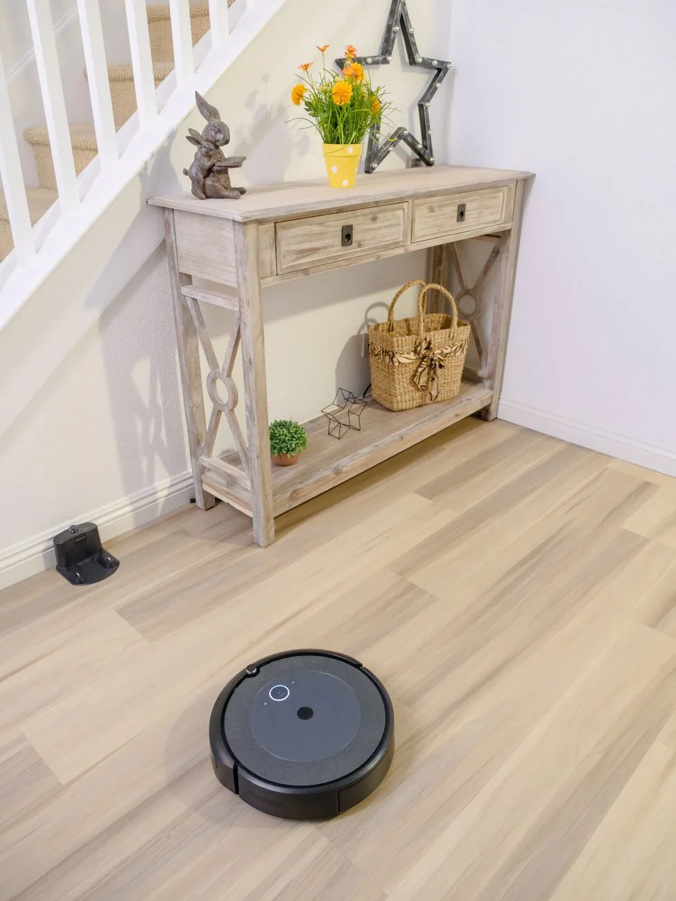 robot sprzątający na podłodze przy drewnianej konsoli — Dlaczego nie bierzemy Xiaomi Robot Vacuum E10 do naprawy