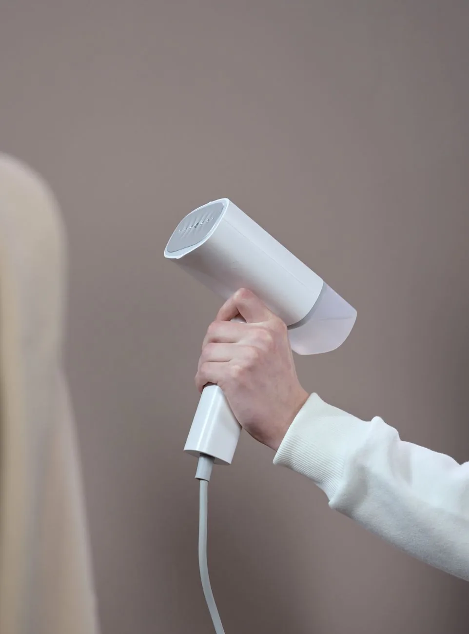 dłoń trzymająca białą suszarkę na szarym tle — GHD Helios w zgłoszeniu — jak odpowiadamy i co radzimy