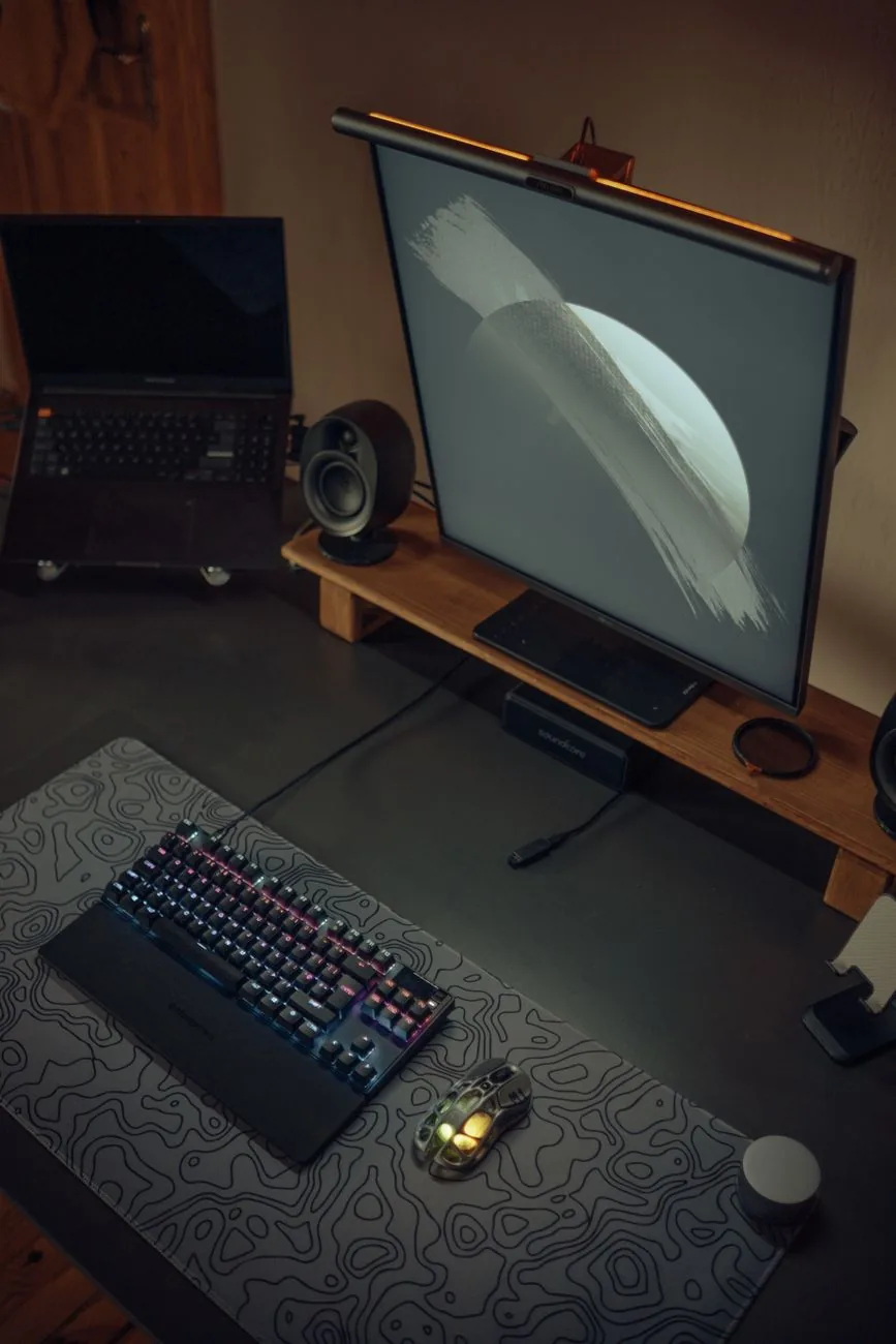 dwa ekrany i podświetlana klawiatura RGB na ciemnym biurku — Gigabyte M32U poza naszym warsztatem — gdzie szukać pomocy