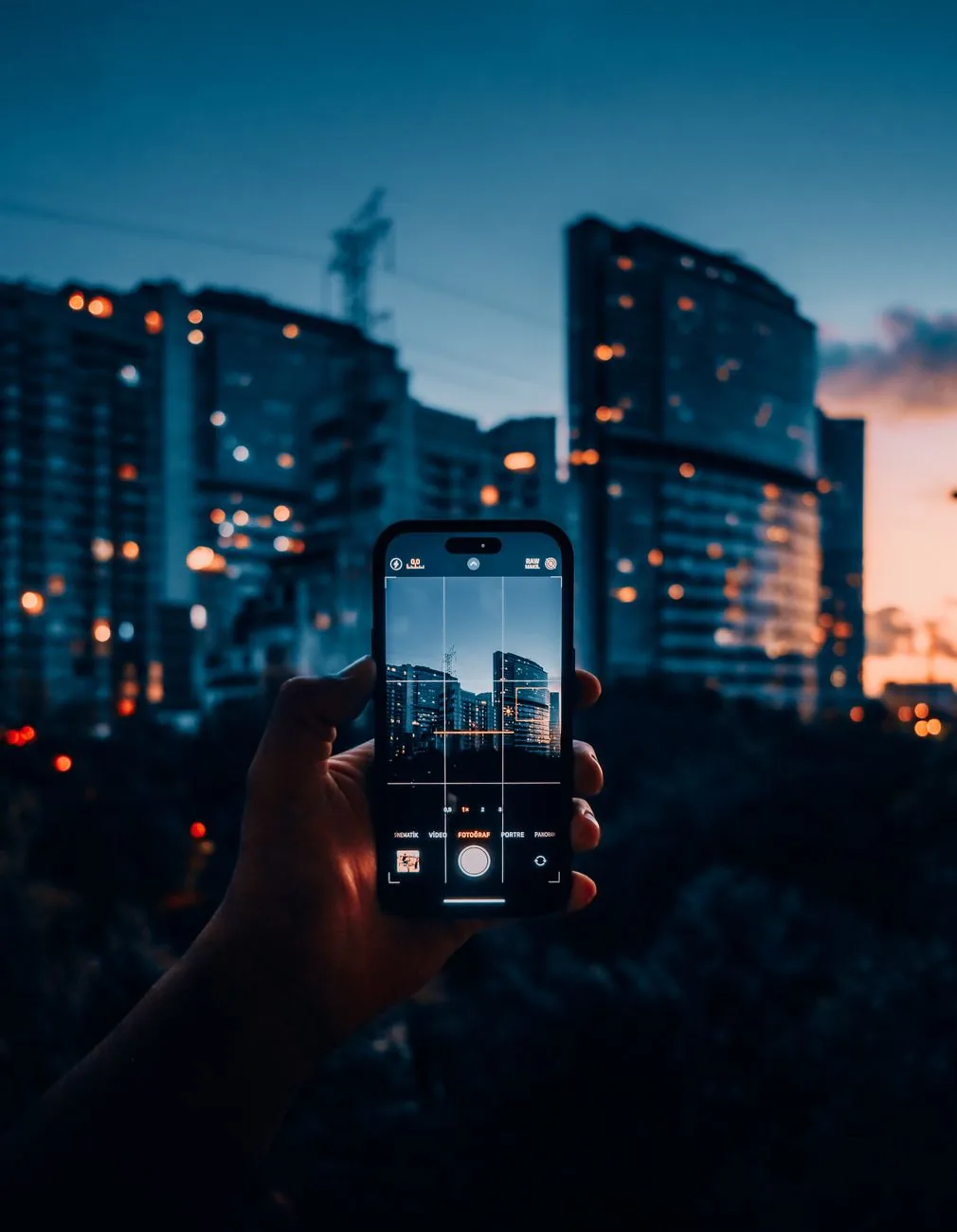dłoń ze smartfonem na tle wieżowców o zmierzchu — Google Pixel 8 poza naszym warsztatem — gdzie szukać pomocy