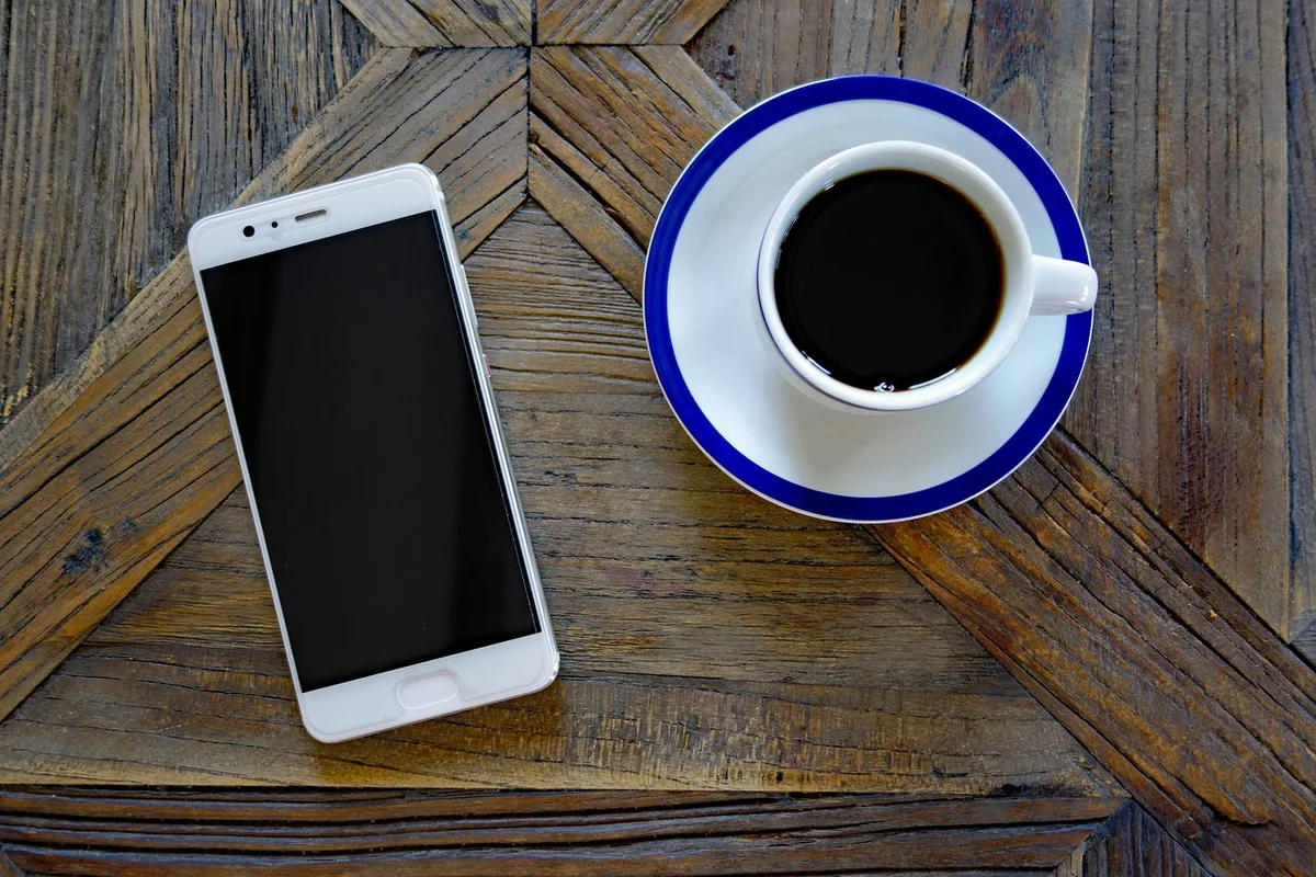 smartfon Huawei leżący obok dzbanka i filiżanki kawy — Huawei Mate X3 poza naszym warsztatem — gdzie szukać pomocy