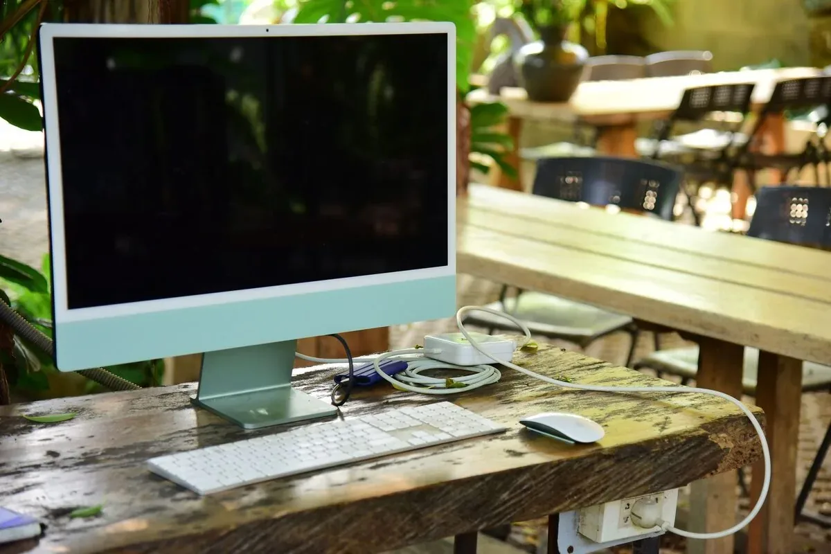 iMac na drewnianym stole na tarasie, rozpoznawalna sylwetka i klawiatura Apple — iMac 21,5 cala 4K (2015) — czego przy tym sprzęcie nie zrobimy