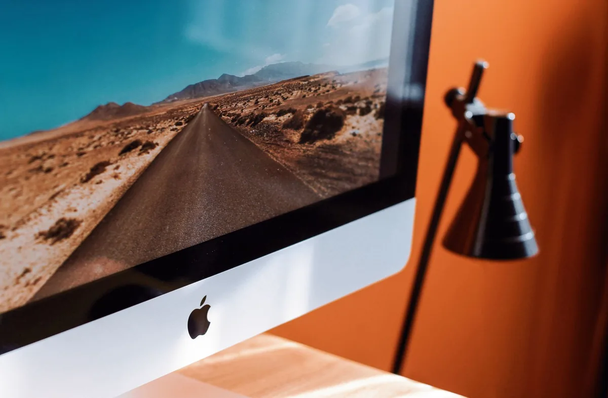 komputer iMac z tapetą pustynnej drogi i lampka na biurku — iMac 27 cali 5K (2014) a zakres naszego serwisu — czym zajmujemy się zamiast