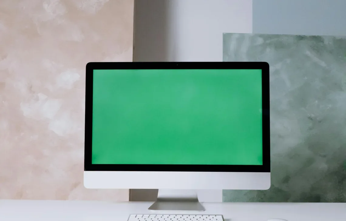 Monitor iMac z zielonym ekranem na biurku, widoczna sylwetka Apple — iMac 27 cali 5K (2020) poza naszym warsztatem — gdzie szukać pomocy