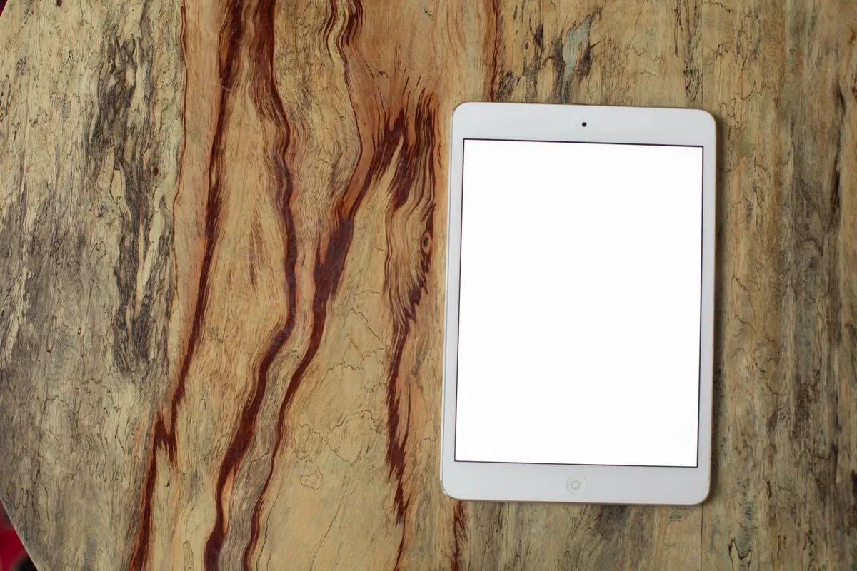biały tablet leżący na teksturowanym drewnianym blacie — iPad 8. generacji w zgłoszeniu — jak odpowiadamy i co radzimy