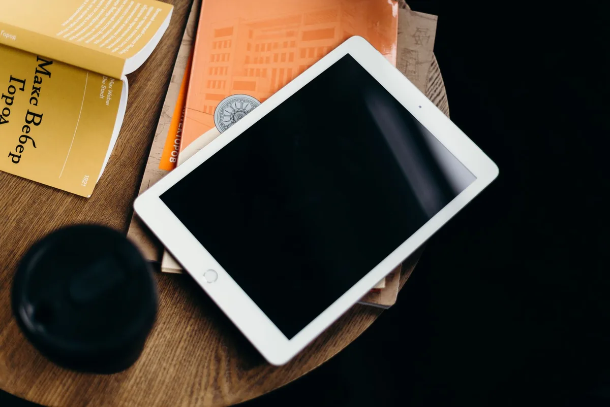 tablet iPad na stoliku obok stosu książek — iPad mini 6 poza naszym warsztatem — gdzie szukać pomocy