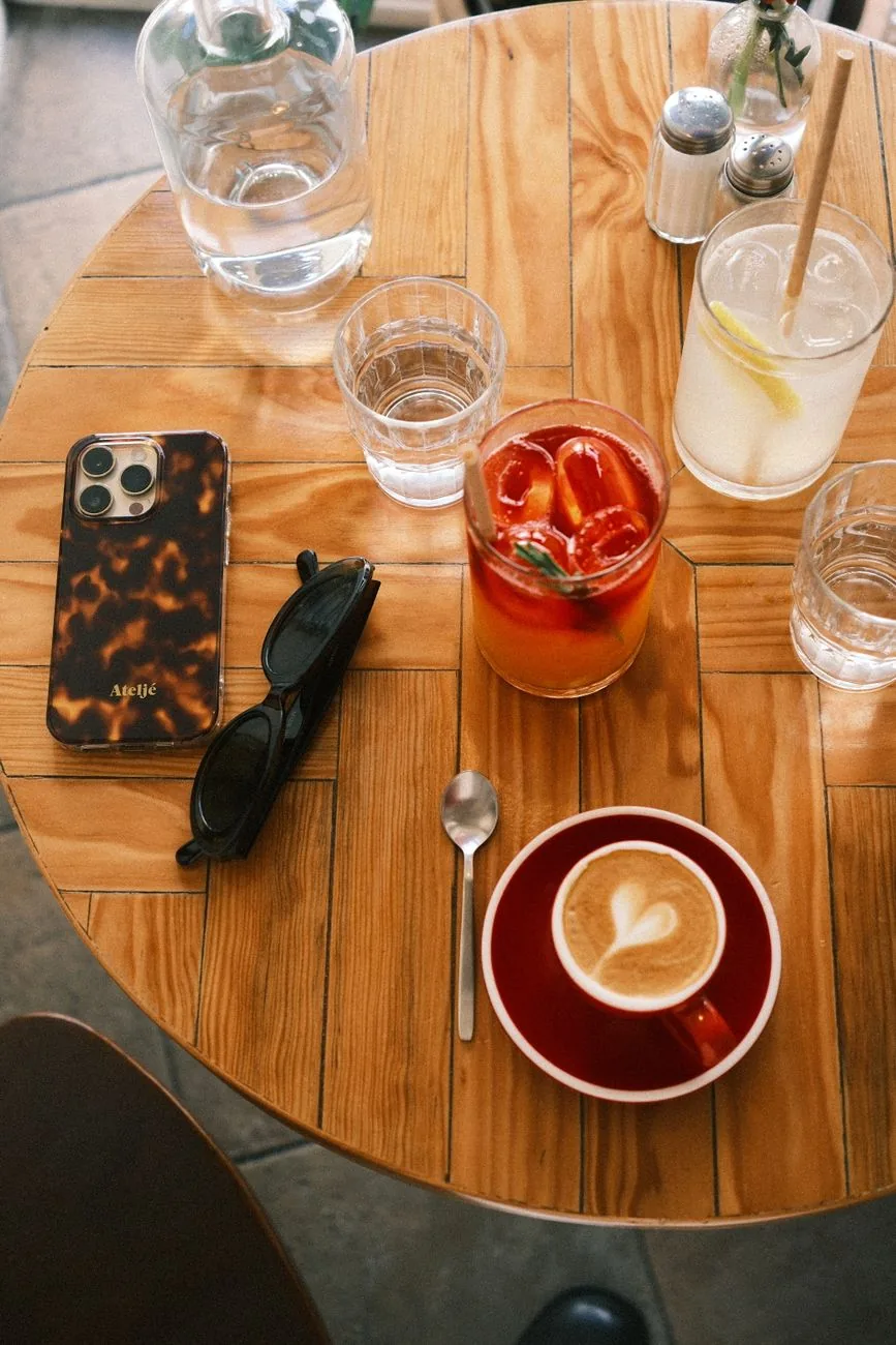 iPhone, okulary przeciwsłoneczne i napoje na kawiarnianym stoliku — iPhone 15 Pro w zgłoszeniu — jak odpowiadamy i co radzimy
