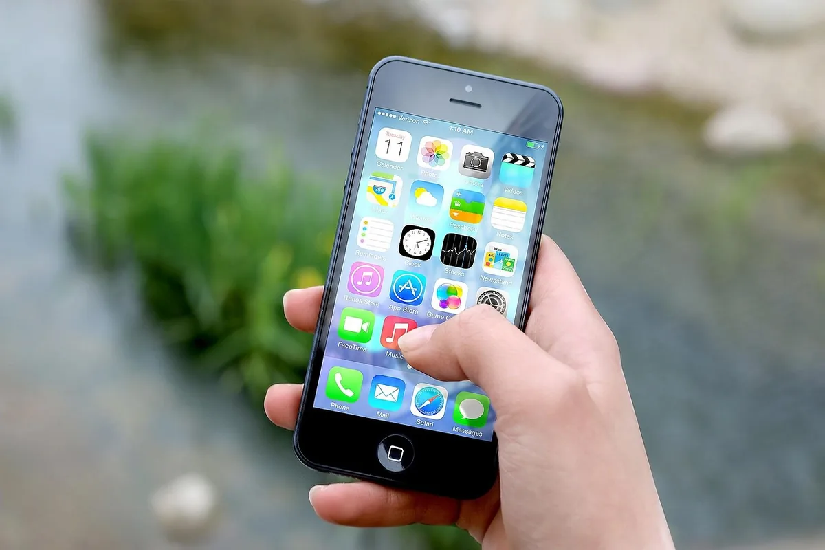 dłoń trzymająca smartfon iphone z ikonami aplikacji — iPhone 16 a zakres naszego serwisu — czym zajmujemy się zamiast