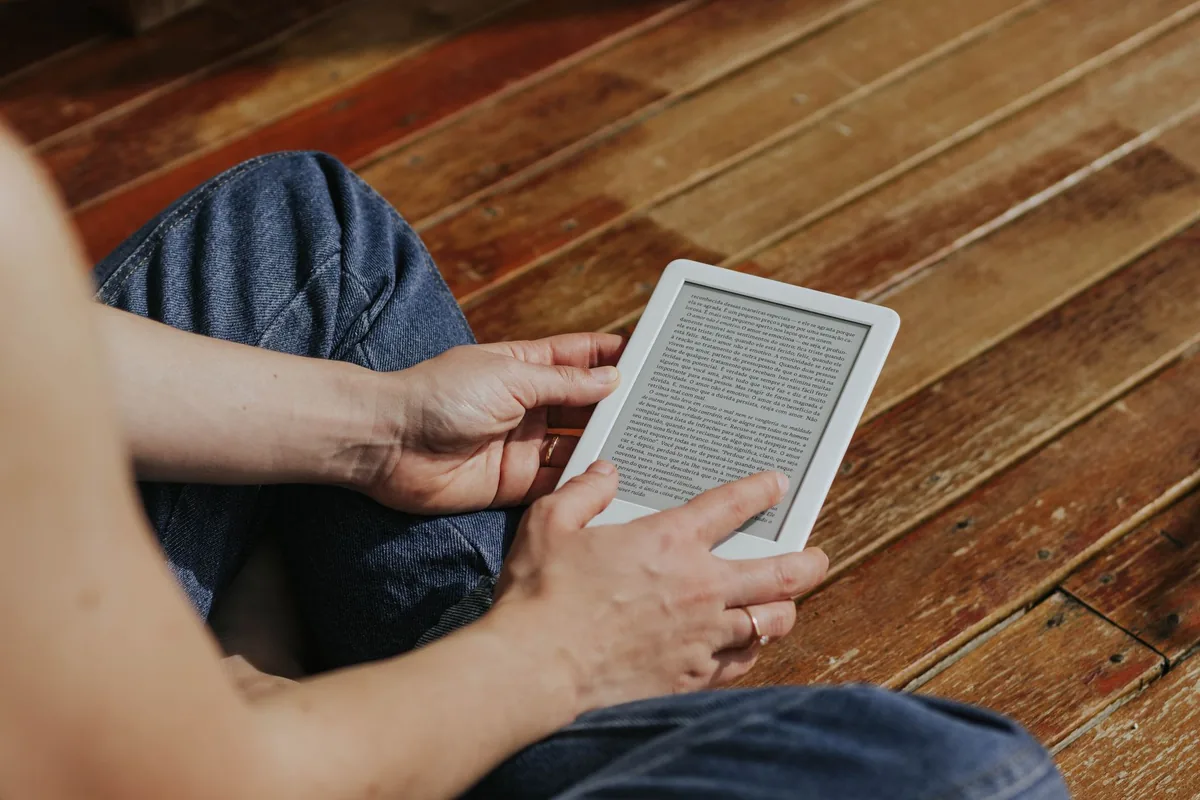 dłonie trzymające czytnik e-booków na drewnianej podłodze — Kobo Libra 2 w zgłoszeniu — jak odpowiadamy i co radzimy