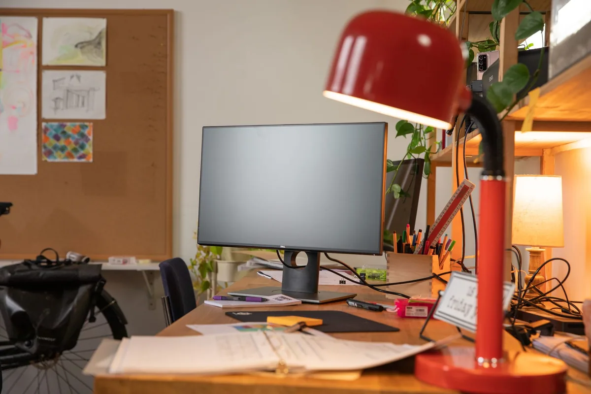 monitor komputerowy z czerwoną lampką biurkową i przyborami — Lenovo ThinkVision E24-30 a zakres naszego serwisu — czym zajmujemy się zamiast