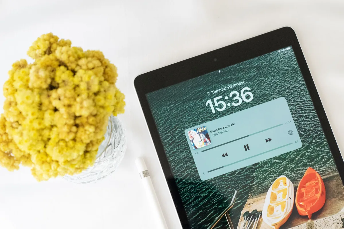 tablet z odtwarzaczem muzyki obok wazonu z żółtymi kwiatami — Lenovo Yoga Tab 11 a zakres naszego serwisu — czym zajmujemy się zamiast