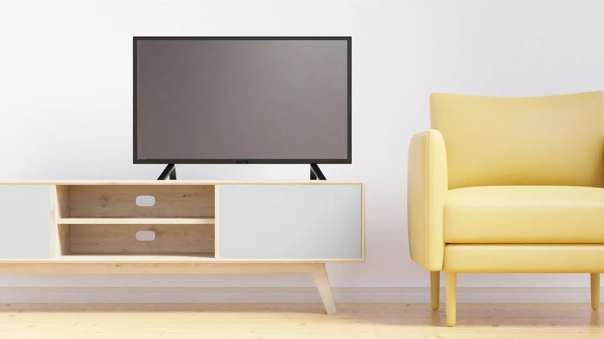płaski telewizor nad drewnianą szafką obok żółtego fotela — LG OLED C4 a zakres naszego serwisu — czym zajmujemy się zamiast