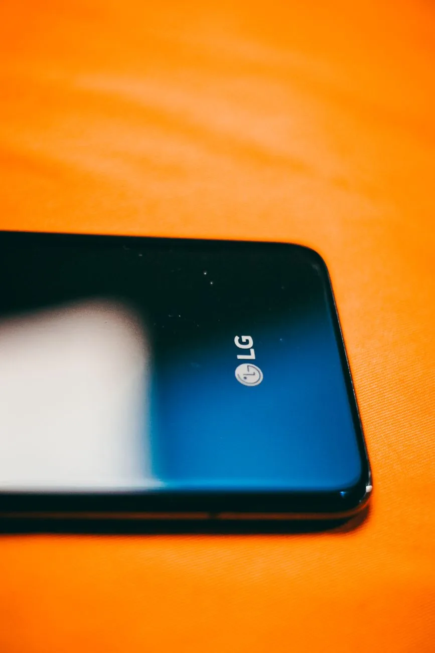 czarny smartfon LG na jaskrawopomarańczowym tle — LG Velvet a zakres naszego serwisu — czym zajmujemy się zamiast