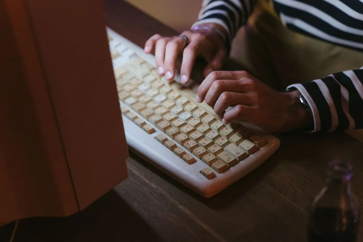 dłonie piszące na beżowej klawiaturze retro — Logitech G915 TKL a zakres naszego serwisu — czym zajmujemy się zamiast
