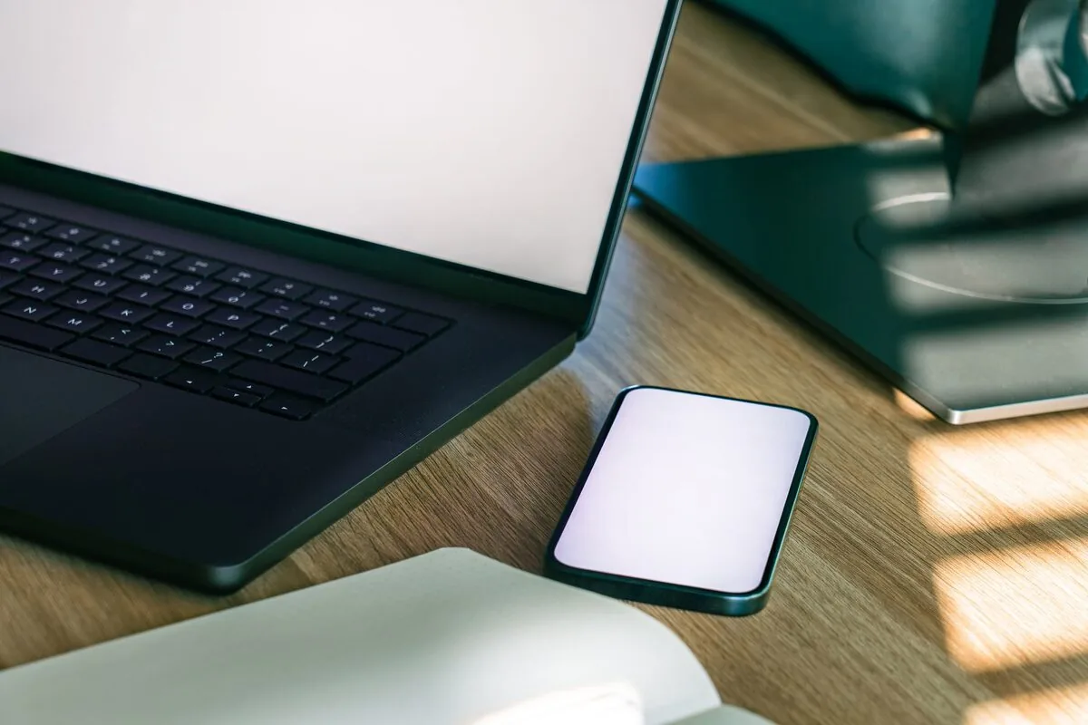 zbliżenie klawiatury MacBooka i telefonu leżącego obok na biurku — Mac mini M1 (2020) — czego przy tym sprzęcie nie zrobimy