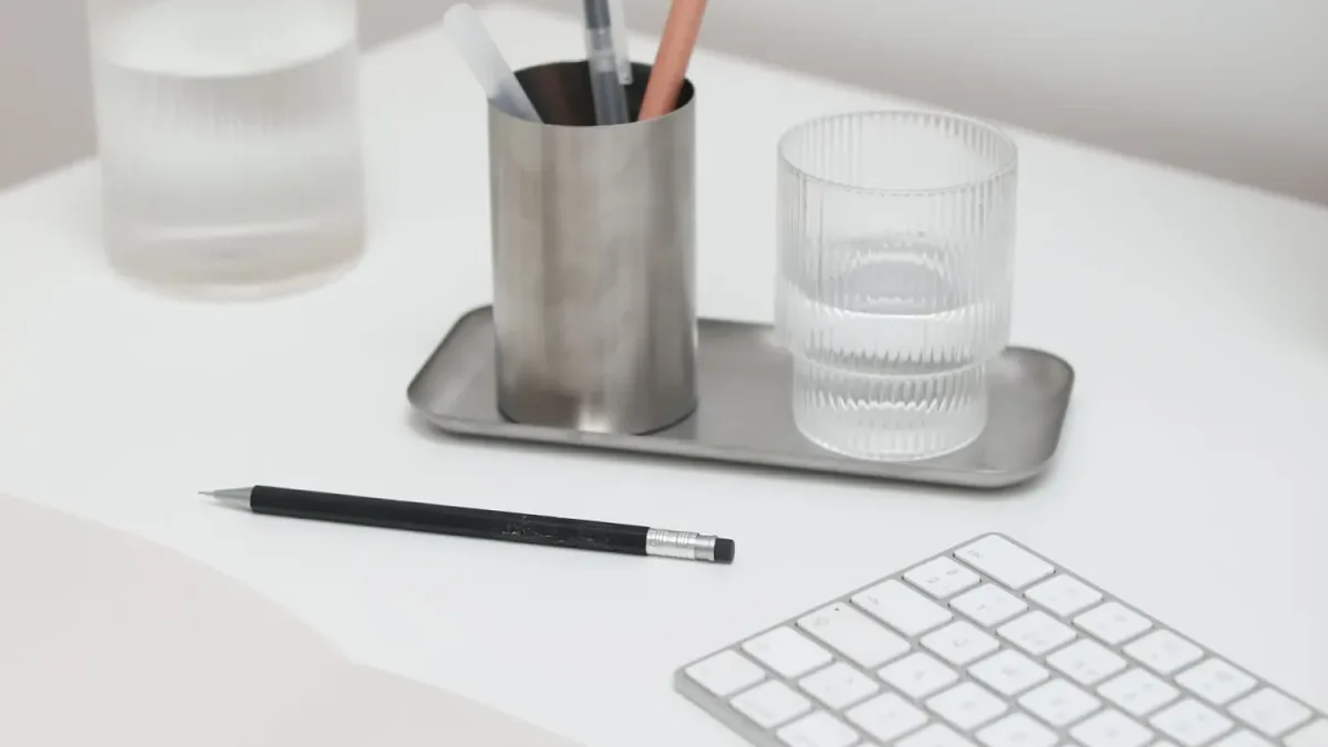 Biurko z białą klawiaturą Apple Magic Keyboard, szklanką i przyborami — Mac Pro M2 Ultra (2023) a zakres naszego serwisu — czym zajmujemy się zamiast