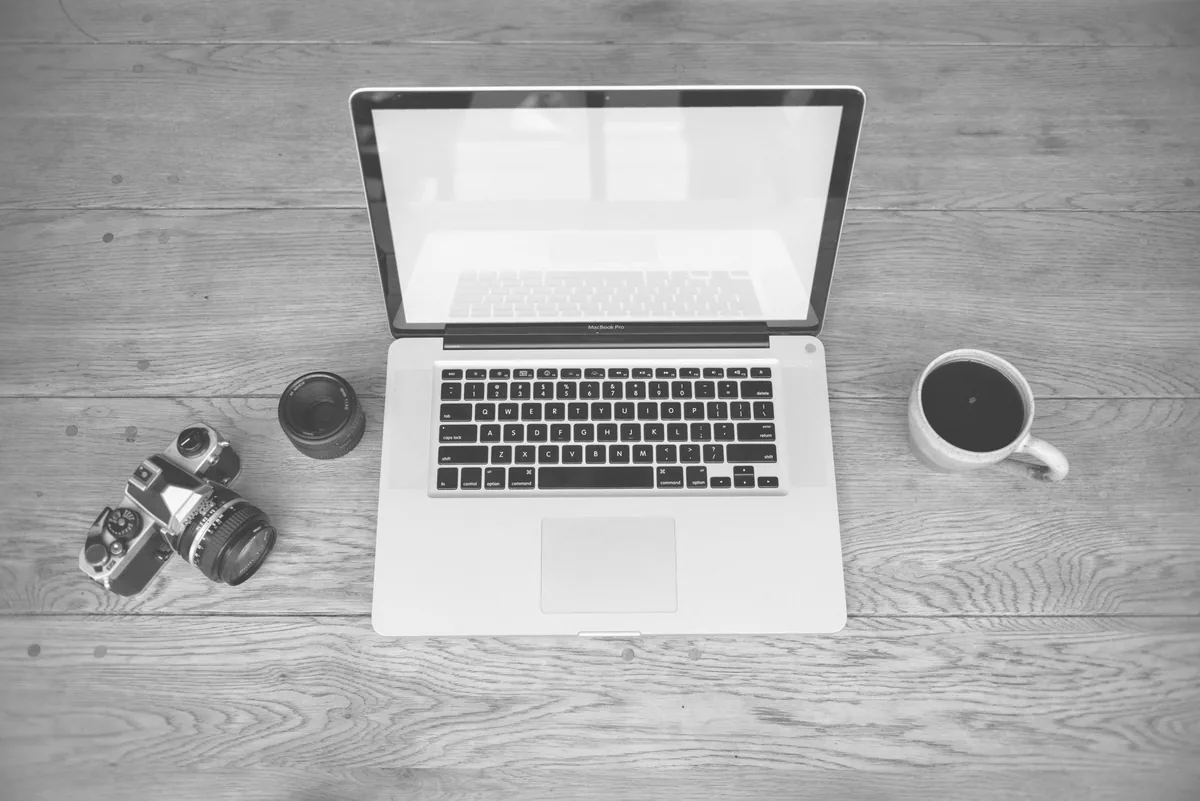 laptop, aparat, obiektyw i filiżanka kawy na drewnianym biurku — MacBook 12 cali (2016) a zakres naszego serwisu — czym zajmujemy się zamiast