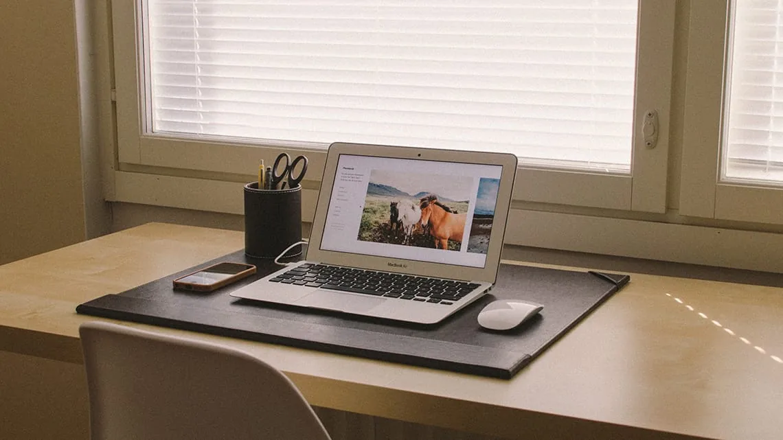 MacBook Air i iPhone na biurku przy oknie z żaluzjami — MacBook Air 13 cali (2012) — czego przy tym sprzęcie nie zrobimy