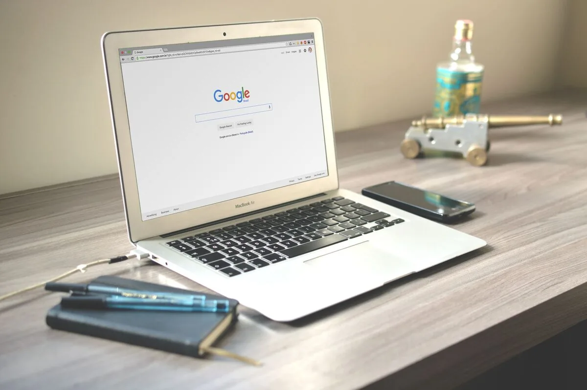 otwarty MacBook Air z wyszukiwarką Google na ekranie i telefonem obok — MacBook Air 13 cali Retina (2019) — czego przy tym sprzęcie nie zrobimy