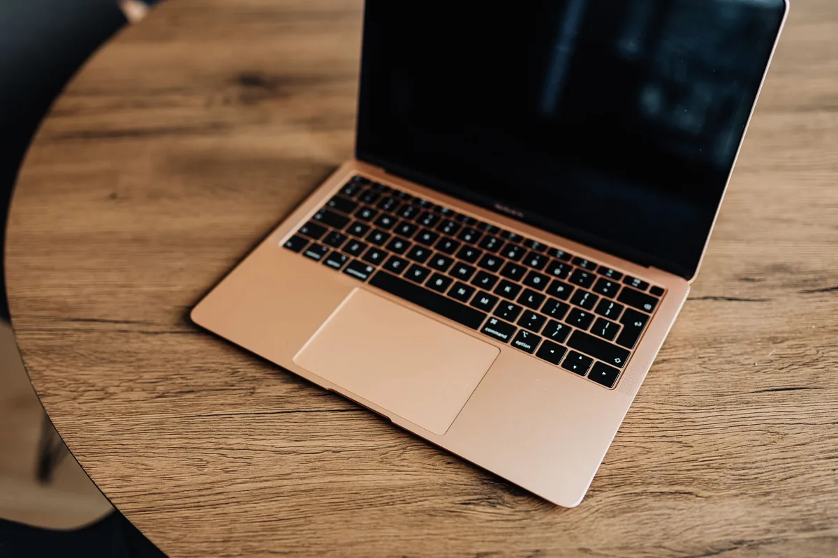 złoty laptop na drewnianym stole widziany z góry — MacBook biały (2010) a zakres naszego serwisu — czym zajmujemy się zamiast