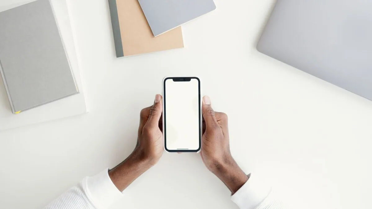 dłonie trzymające iPhone'a obok srebrnego laptopa typu MacBook — MacBook Pro 13 cali (2017) a zakres naszego serwisu — czym zajmujemy się zamiast