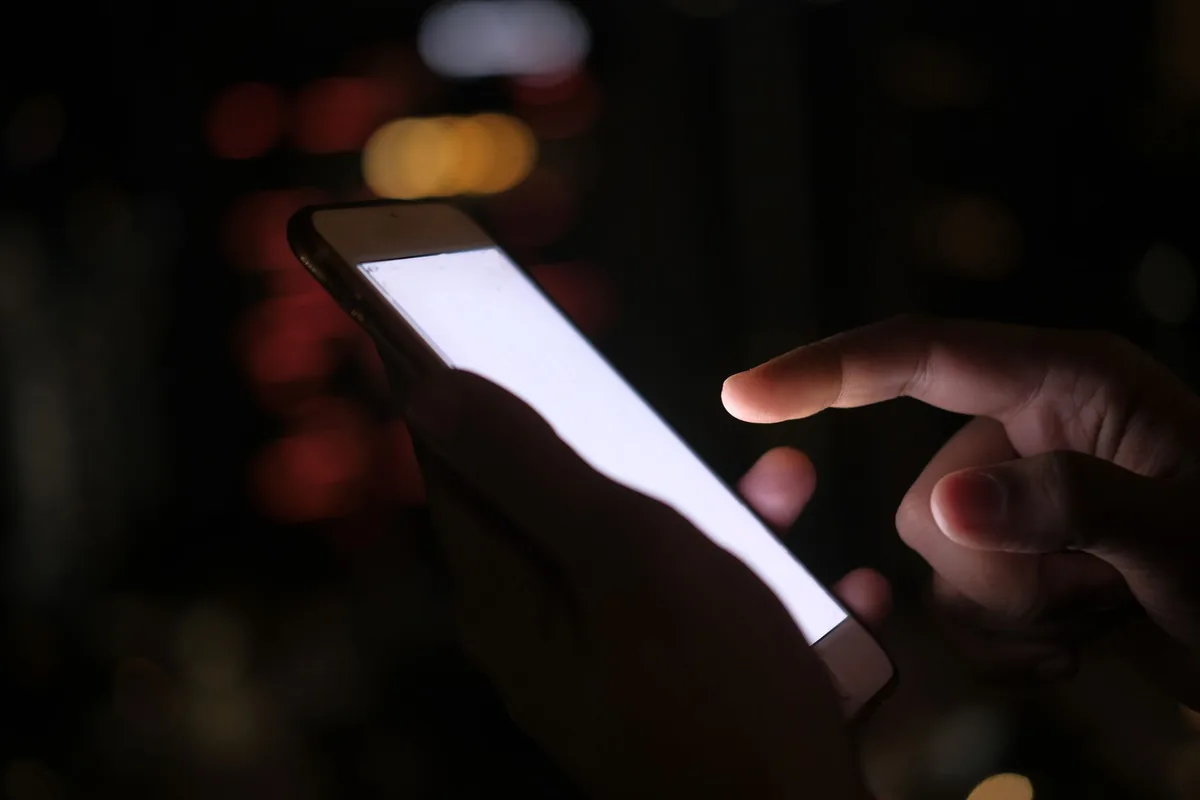 dłoń ze smartfonem na tle świateł miasta nocą — Motorola Edge 20 poza naszym warsztatem — gdzie szukać pomocy