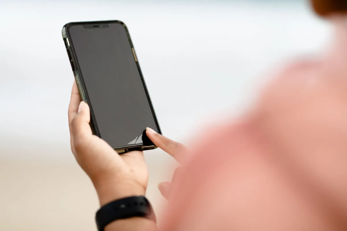 dłoń dotykająca ekranu smartfona na zewnątrz — Motorola Edge 40 Pro poza naszym warsztatem — gdzie szukać pomocy
