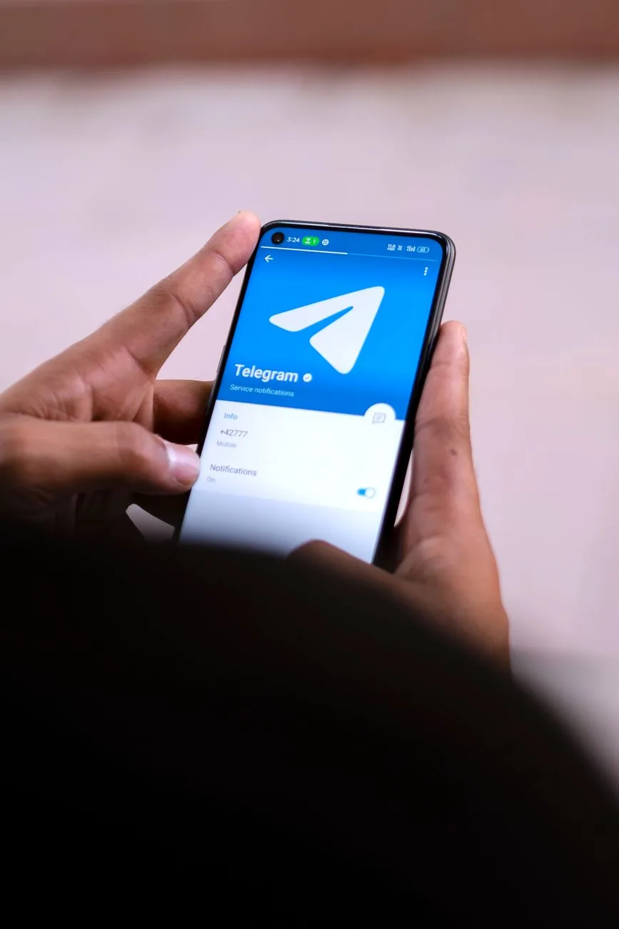 dłonie trzymające smartfon z otwartą aplikacją telegram — Motorola Moto G23 poza naszym warsztatem — gdzie szukać pomocy