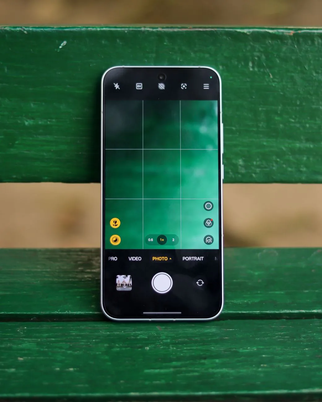 smartfon z aplikacją aparatu na zielonej drewnianej ławce — Motorola Moto G84 — czego przy tym sprzęcie nie zrobimy