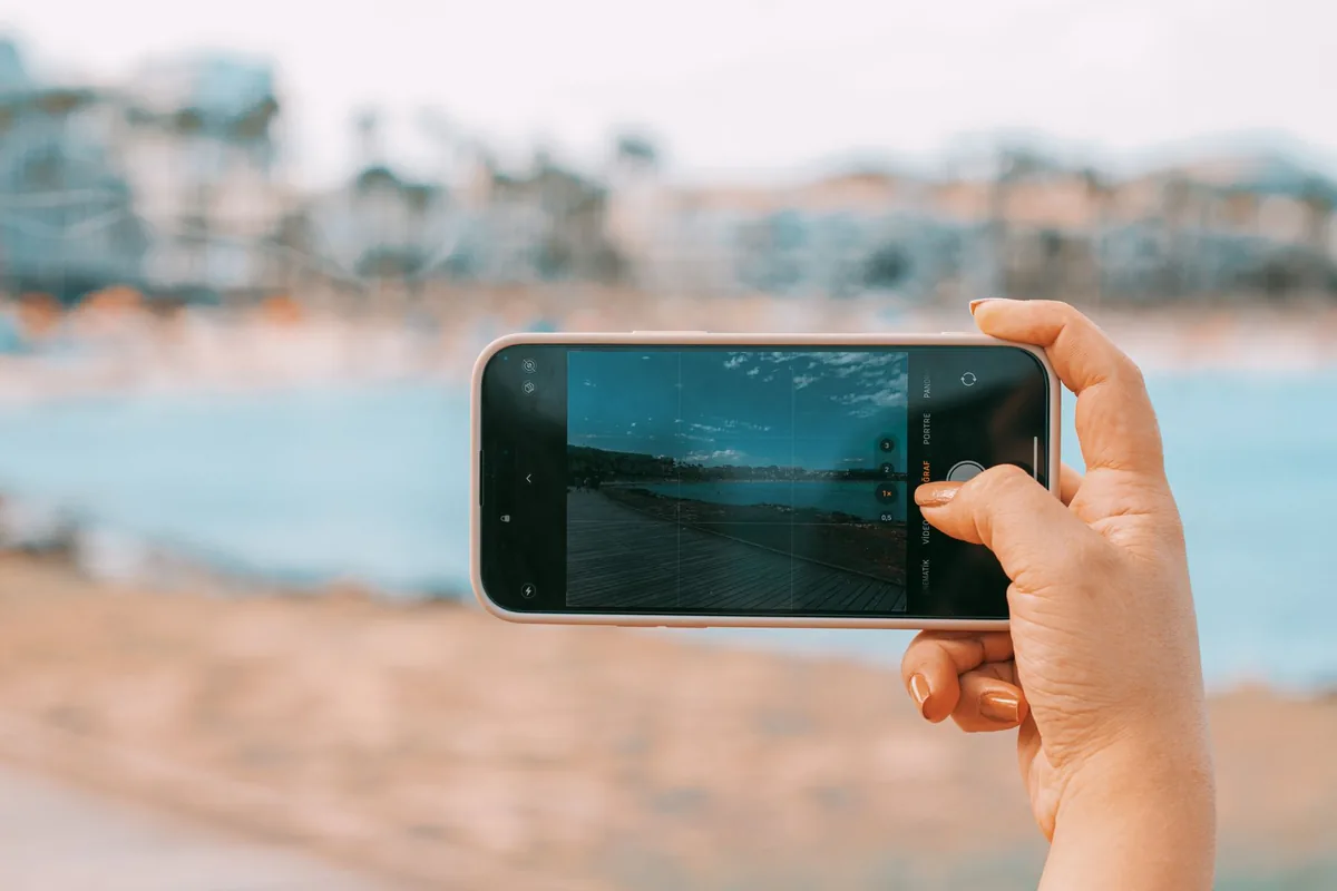 dłoń ze smartfonem na tle plaży w palmie — Motorola Razr 50 a zakres naszego serwisu — czym zajmujemy się zamiast