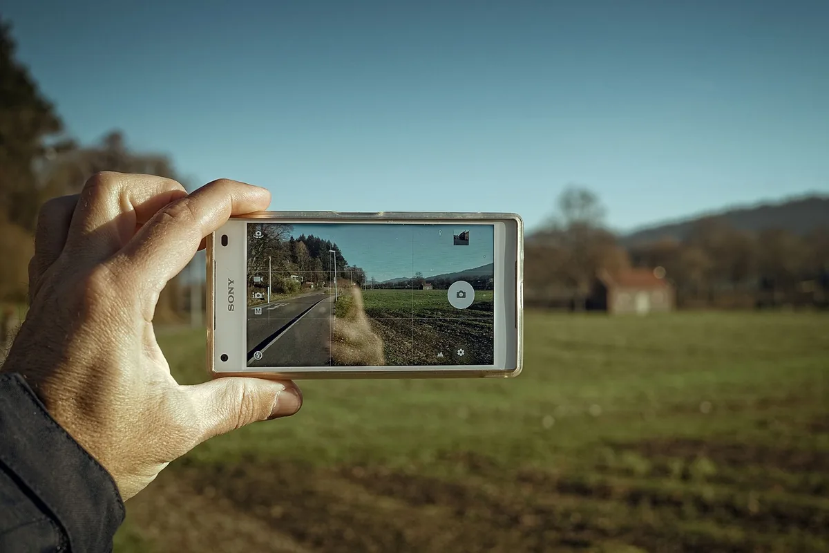 dłoń ze smartfonem skierowanym na wiejską drogę — Motorola ThinkPhone w zgłoszeniu — jak odpowiadamy i co radzimy