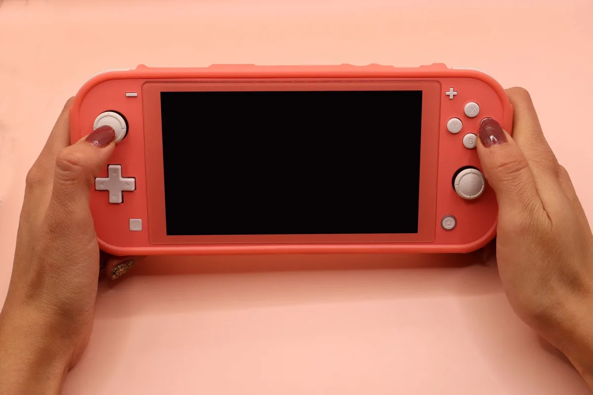 dłonie trzymające różową konsolę Nintendo Switch Lite — Nintendo Switch Lite Hyrule a zakres naszego serwisu — czym zajmujemy się zamiast