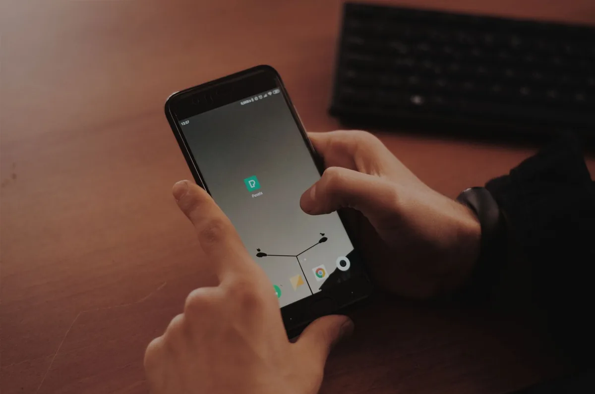 dłonie obsługujące nowoczesny smartfon na drewnianym biurku — OnePlus 10T poza naszym warsztatem — gdzie szukać pomocy