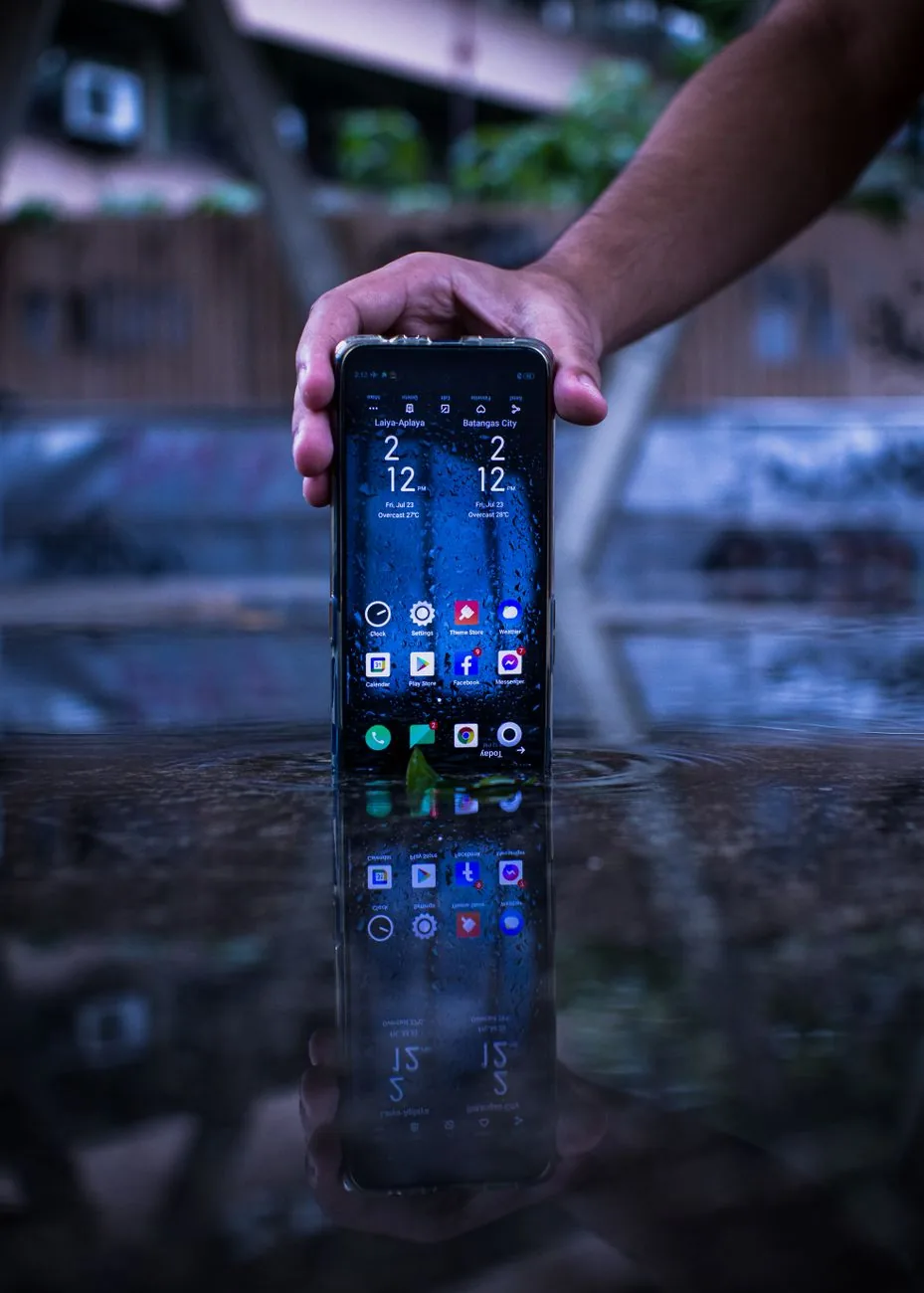 dłoń ze smartfonem odbijająca się w kałuży — OnePlus 13 w zgłoszeniu — jak odpowiadamy i co radzimy