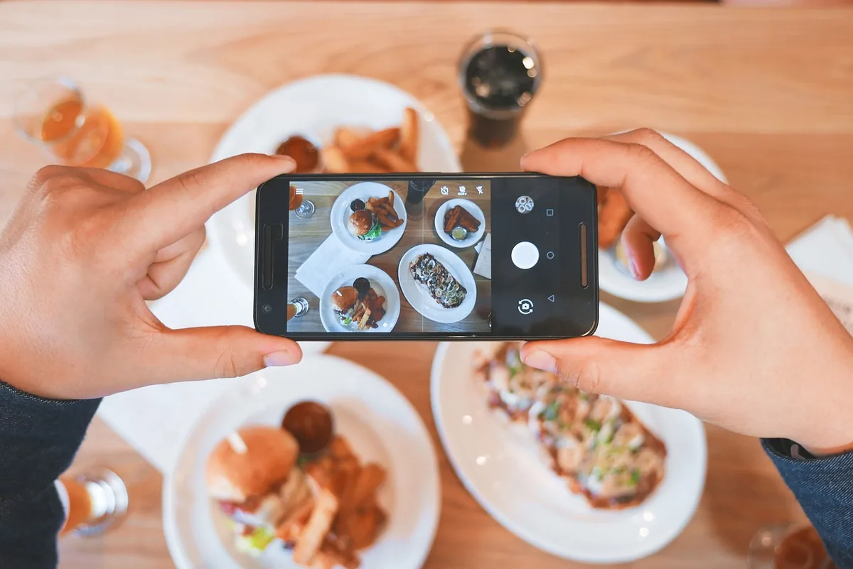dłoń ze smartfonem nad talerzem w restauracji — OnePlus Nord 2T a zakres naszego serwisu — czym zajmujemy się zamiast