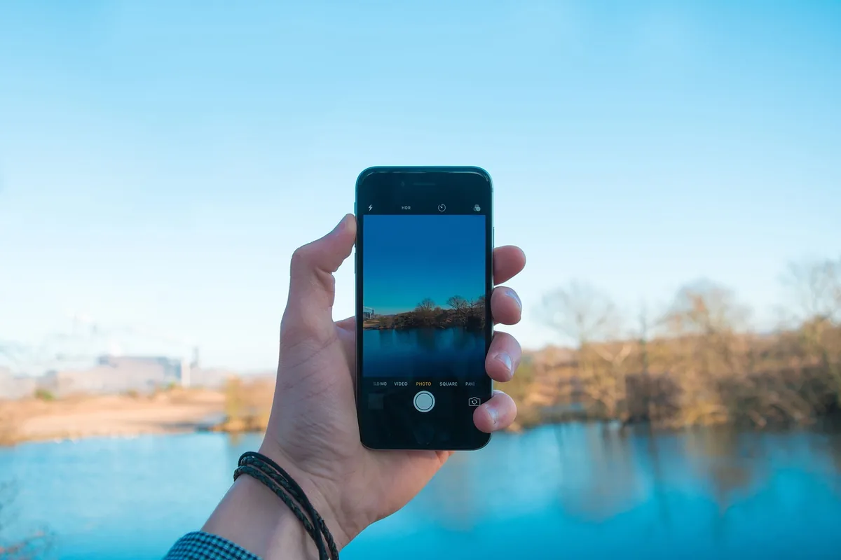 dłoń trzymająca niebieski smartfon nad brzegiem jeziora — OnePlus Nord CE 4 Lite — czego przy tym sprzęcie nie zrobimy