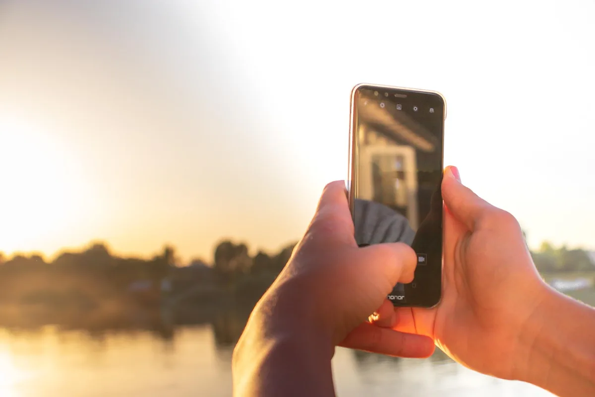 smartfon skierowany ku słonecznemu niebu w plenerze — OnePlus Nord CE poza naszym warsztatem — gdzie szukać pomocy