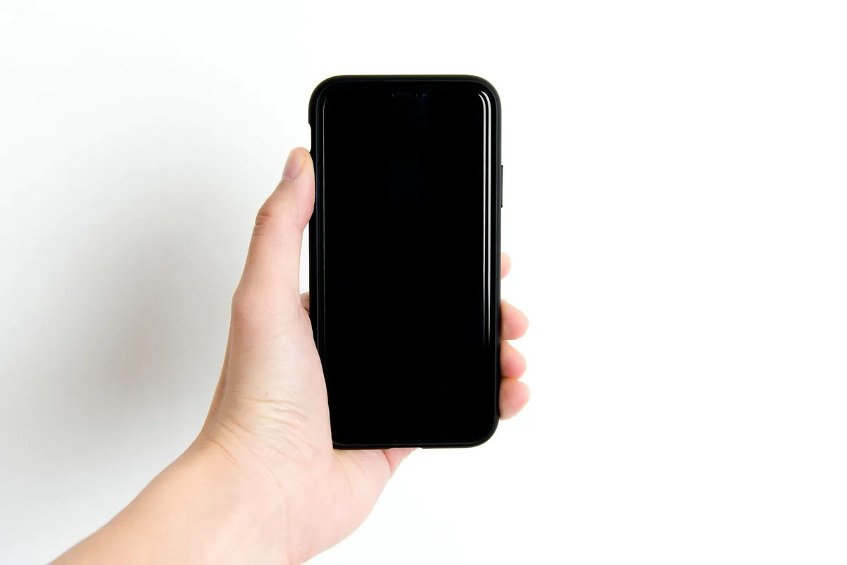 dłoń trzymająca czarny smartfon na gładkim białym tle — OPPO A72 w zgłoszeniu — jak odpowiadamy i co radzimy