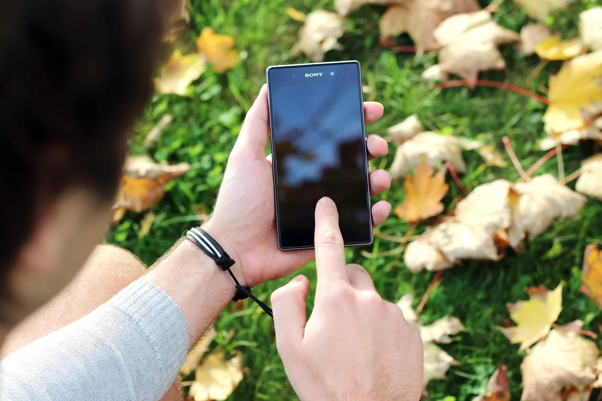 dłoń obsługująca telefon komórkowy na trawie — Oukitel WP21 poza naszym warsztatem — gdzie szukać pomocy