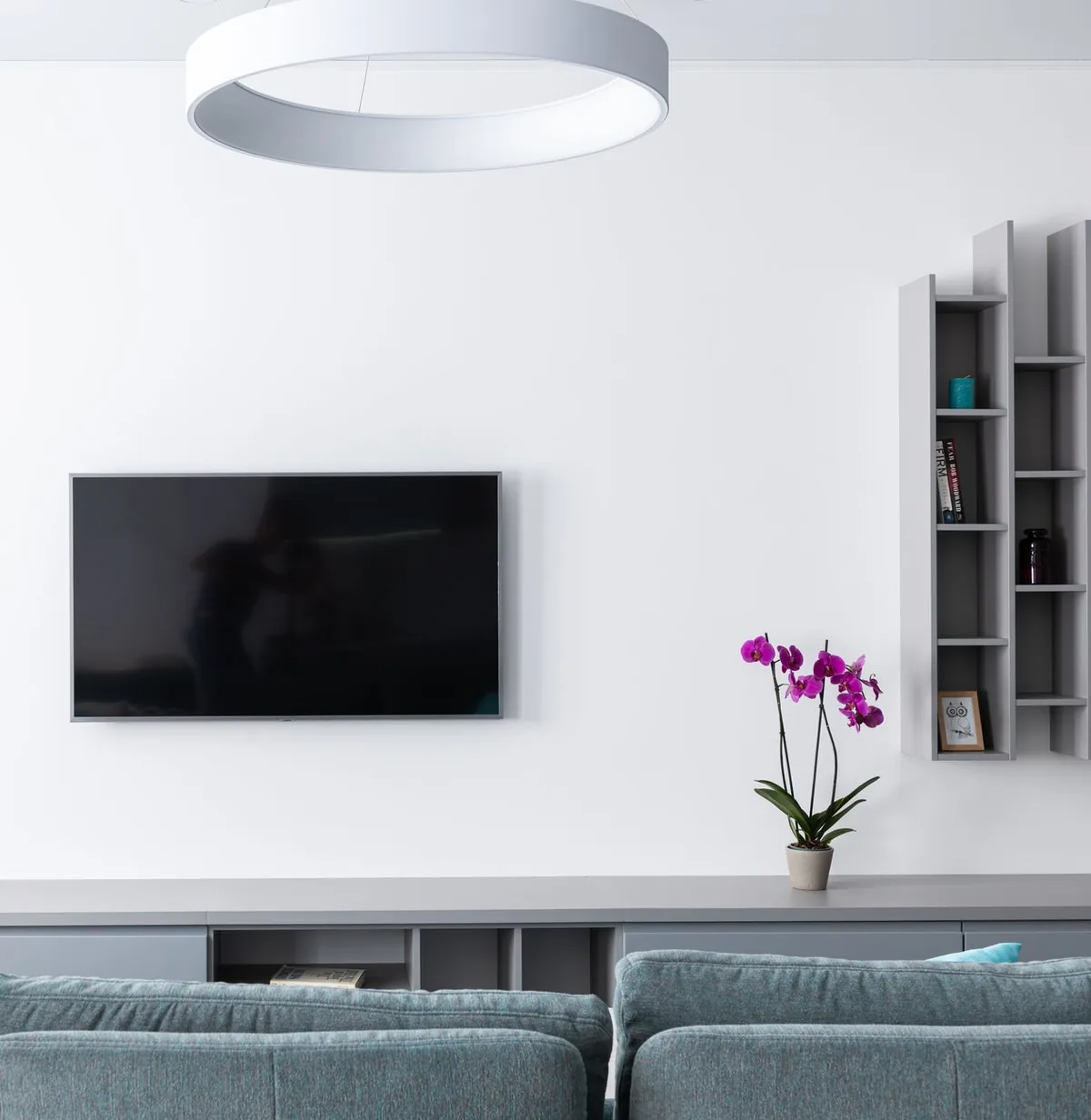telewizor na ścianie i szara sofa w nowoczesnym salonie — Panasonic TX-55MZ1500 — czego przy tym sprzęcie nie zrobimy