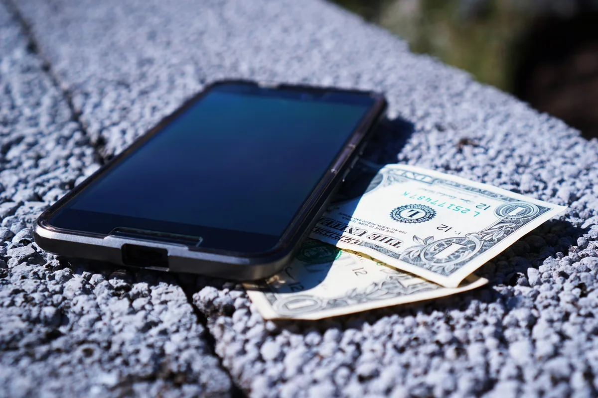smartfon leżący na banknotach dolarowych — POCO M4 Pro poza naszym warsztatem — gdzie szukać pomocy