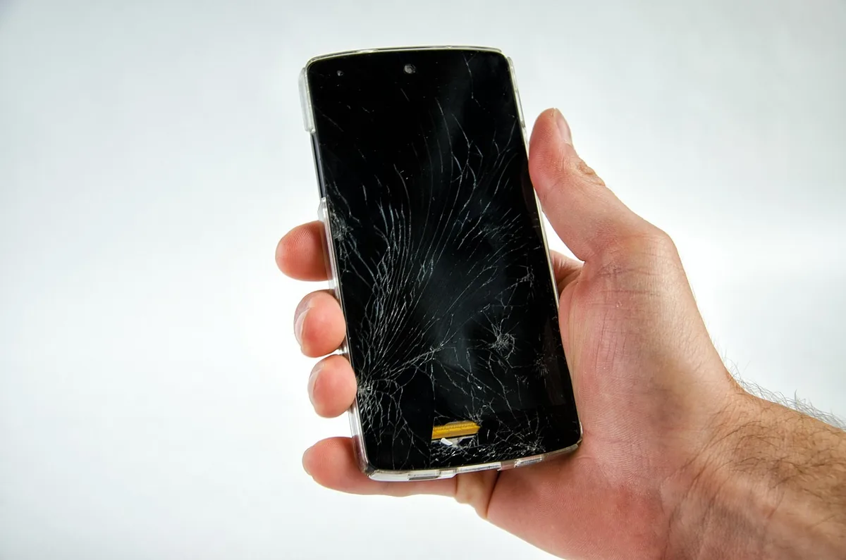 dłoń trzymająca uszkodzony smartfon z rozbitym ekranem — realme 11 w zgłoszeniu — jak odpowiadamy i co radzimy