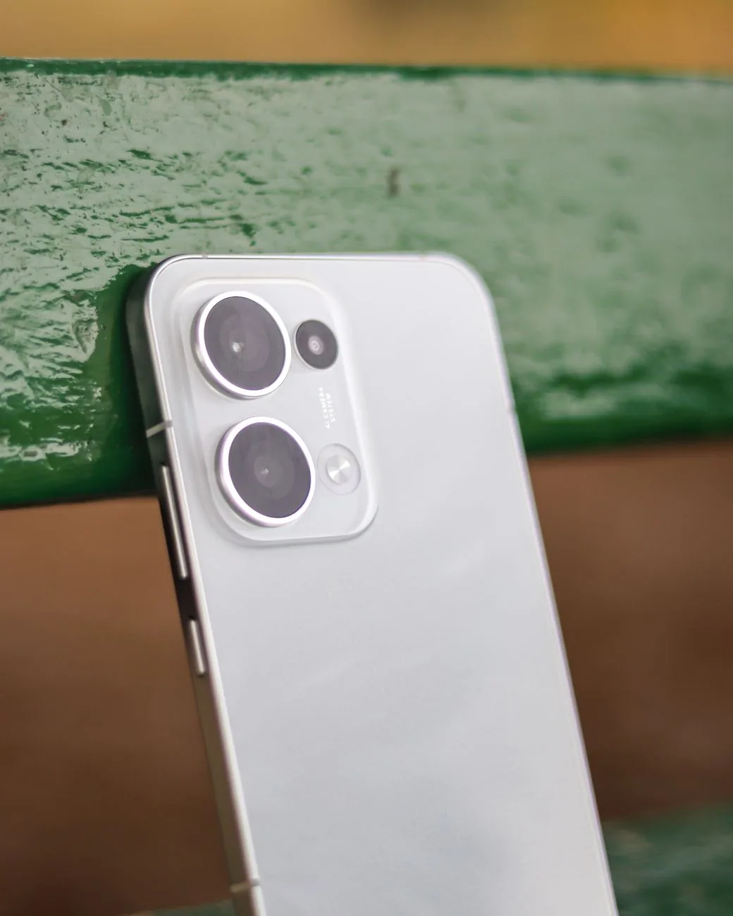 smartfon z podwójnym aparatem na zielonej ławce — realme 12+ poza naszym warsztatem — gdzie szukać pomocy